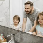 Ojciec z dziećmi uśmiechają się do lustra w rodzinnej łazience