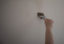 Jak odświeżyć stary korytarz niskim kosztem: malowanie, wymiana uchwytów i szybkie metamorfozy Ręka malująca ścianę pędzlem podczas odświeżania korytarza