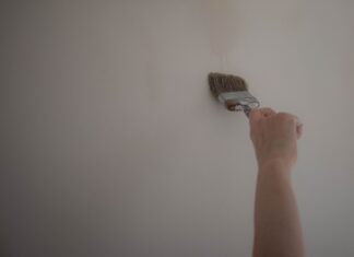 Jak odświeżyć stary korytarz niskim kosztem: malowanie, wymiana uchwytów i szybkie metamorfozy Ręka malująca ścianę pędzlem podczas odświeżania korytarza